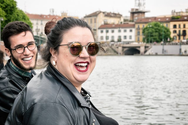 Two friends smiling beside river in European city
