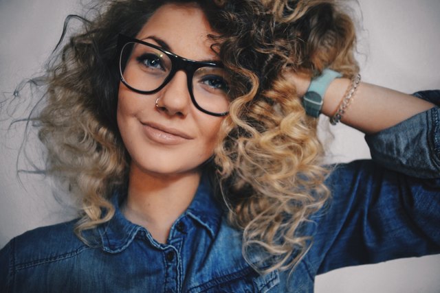 Young woman with curly hair posing with glasses