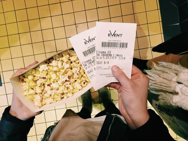 Hands holding popcorn and two movie tickets