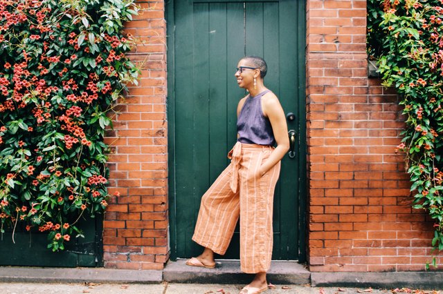 Young relaxed Black woman posing in front of old door outside