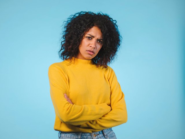 Angry annoyed young woman keeping arms crossed and staring at camera with skeptical and distrustful look