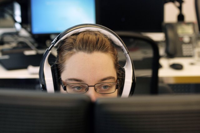 Young white woman wearing headphones at computer station