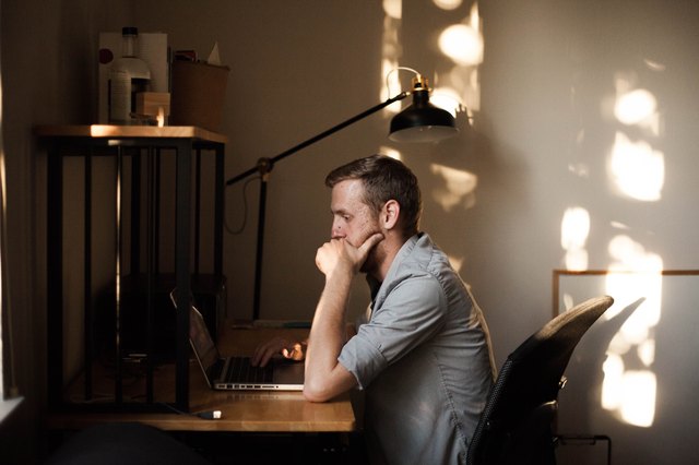 Young white man working on laptop in sunny home office