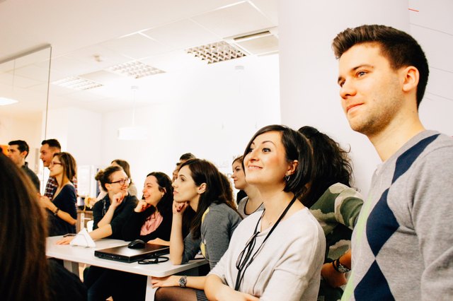 Young startup employees standing/sitting together at presentation