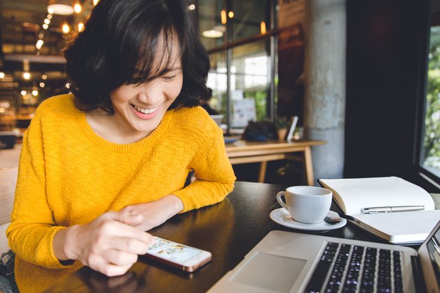 A happy Asian woman smiling chatting with people in her cellphone