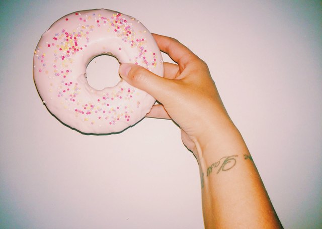 Woman's hand holding pink frosted doughnut with sprinkles