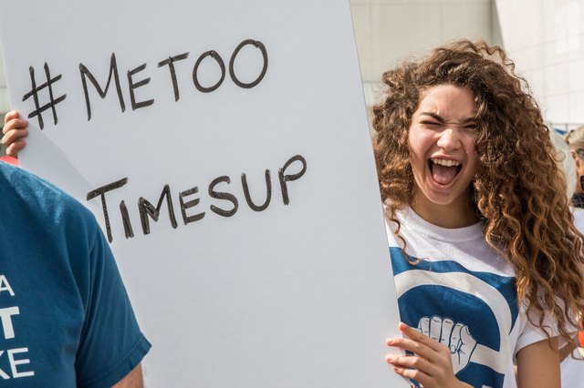 Young woman holding sign with #MeToo and #TimesUp on it