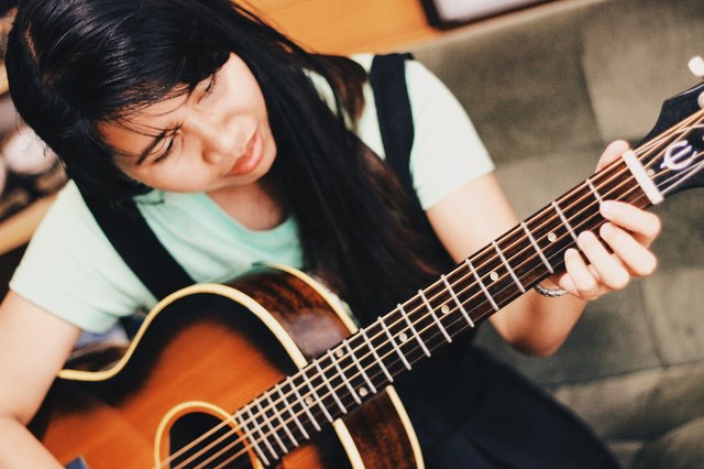 Young woman practices guitar