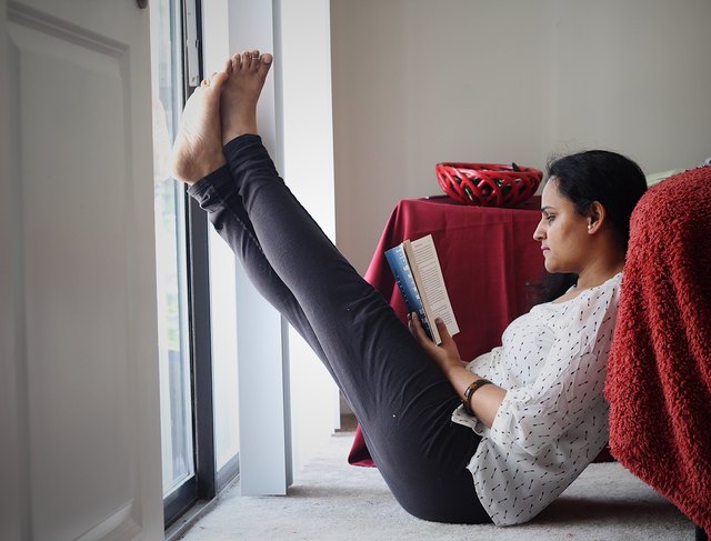 Woman reading a book while propping her feet up on the wall