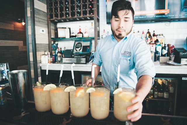Bartender serving five cocktails at bar