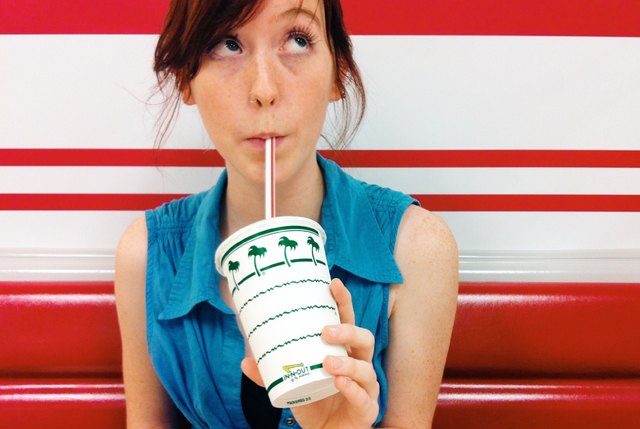 A young woman sips on a milkshake at In-N-Out Burger