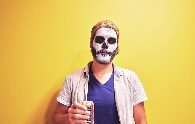 Man dressed as ghost holding can against yellow wall