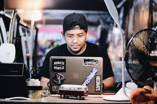 Young man at laptop in cluttered office space