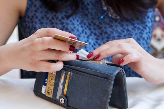 Woman with red fingernails rifling through a wallet