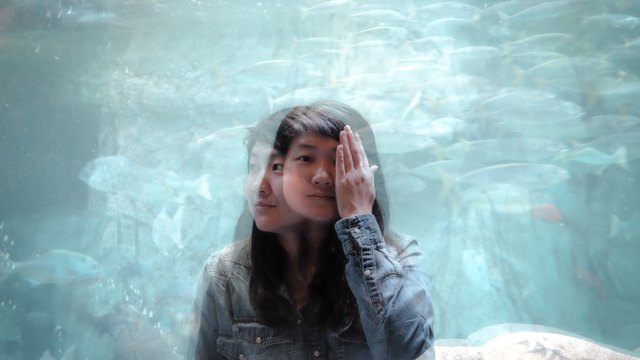 Double exposure of woman at aquarium
