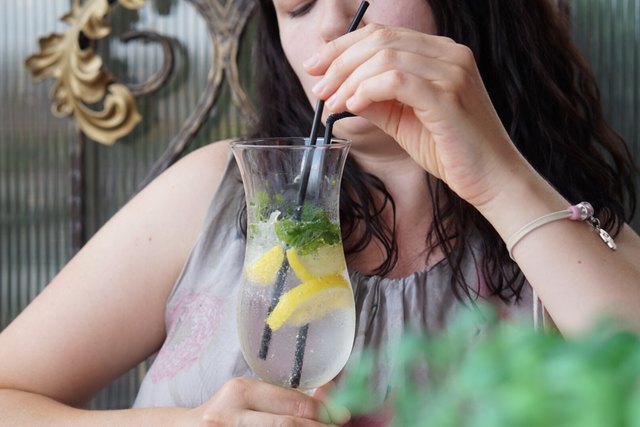 Woman stirring cold drink with straw