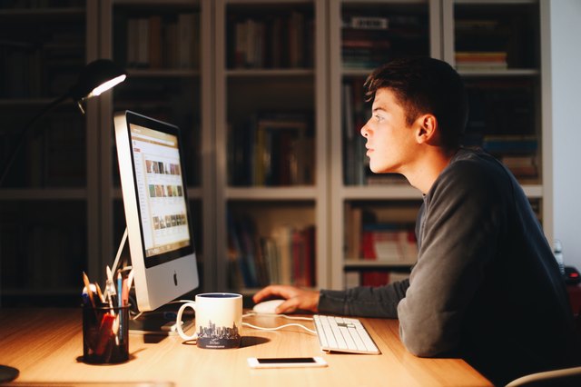 Young white man looking at computer monitor in profile