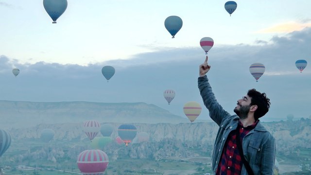 Bearded man posing against scene of hot air balloons