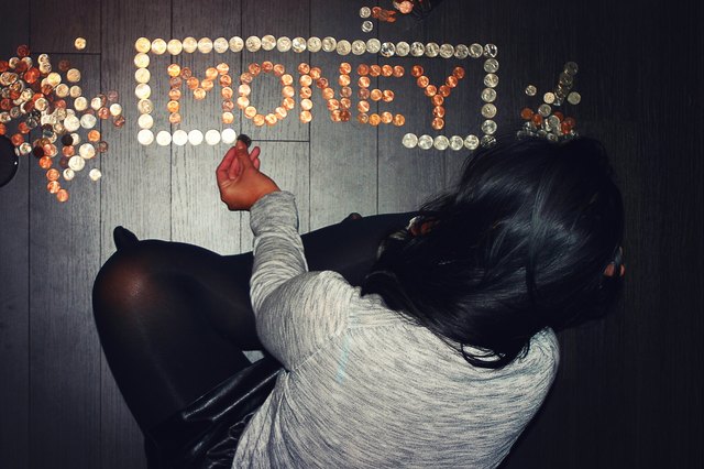 Woman on floor spells out "money" with coins