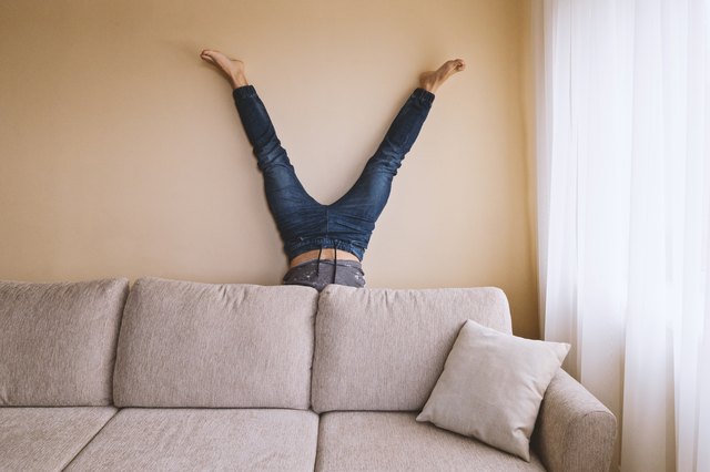 Man doing handstand behind sofa