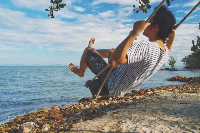 Man on a swing at a tropical beach