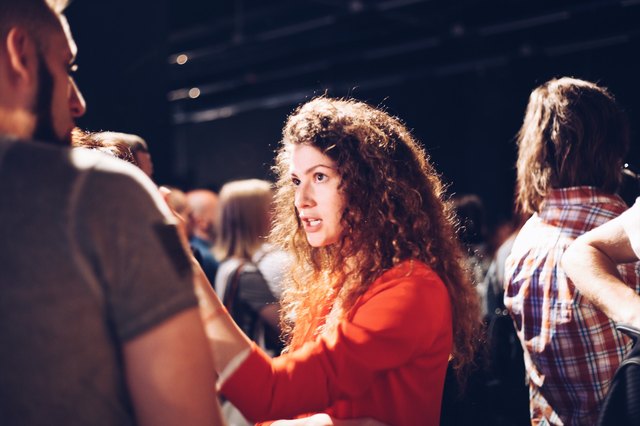 Young woman in red jacket conversing intensely at mixer