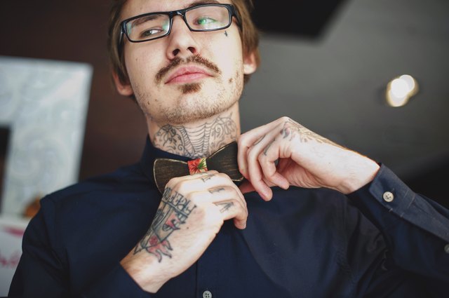 Tattooed man adjusting bow tie