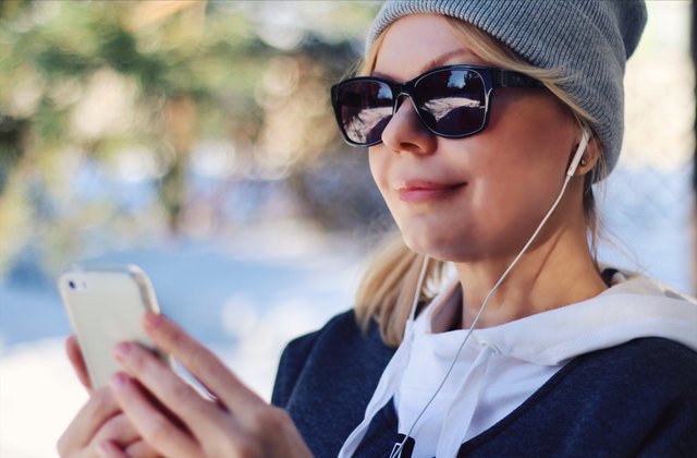 White woman listening to headphones on iPhones