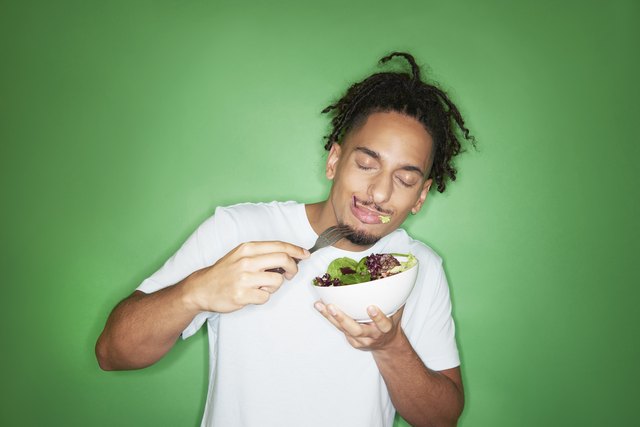 young hipster man eating salad