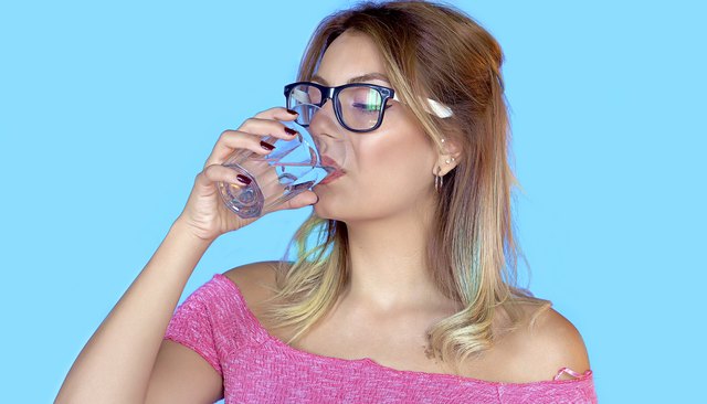 Beautiful young female drinking still clear water