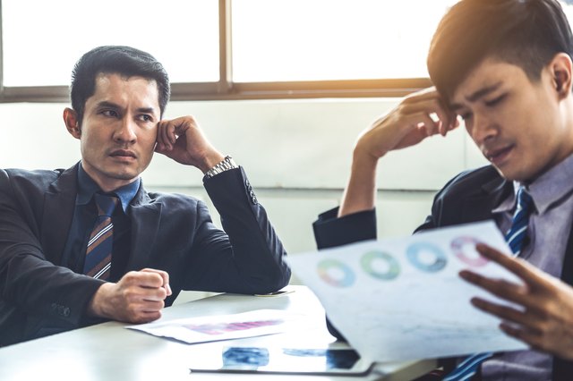 Unhappy business manager and young businessman partner in meeting room at the office. They are under stress because of bad financial document report. Company crisis concept.
