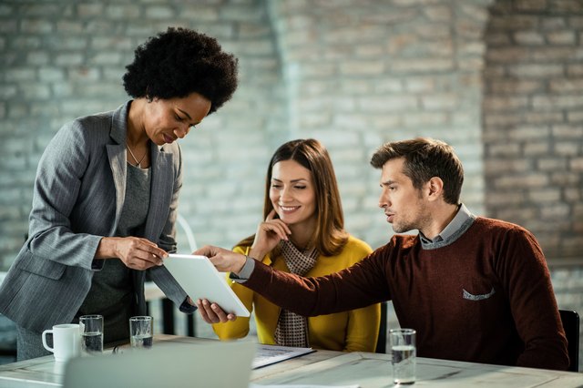 African American financial consultant and couple cooperating while using touchpad on a meeting.
