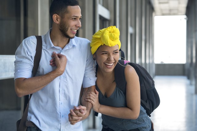 Millennial couple with tattoos walking down the street holding hands