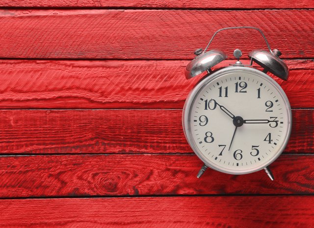 Vintage alarm clock on red wooden background. Top view.