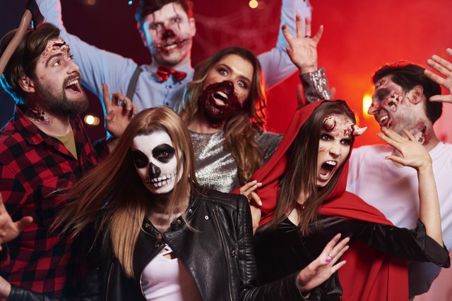 Friends in creepy costumes having fun at Halloween party