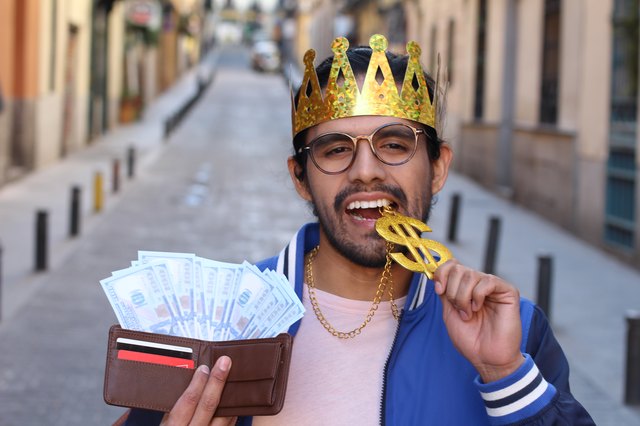 Crowned young guy with full wallet