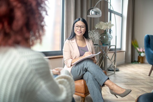 Pleasant psychologist wearing grey trousers smiling to client