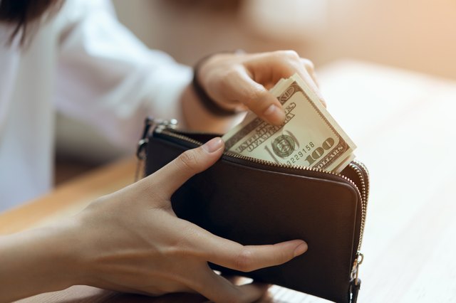 Midsection Of Woman Putting Paper Currencies In Purse