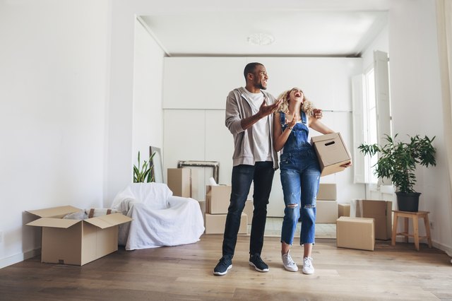 Full length of couple laughing while standing in new home