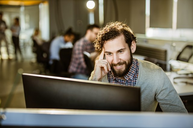 Happy programmer reading codes on desktop PC in the office.