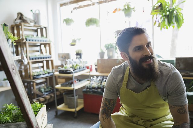Smiling terrarium shop owner with beard looking away