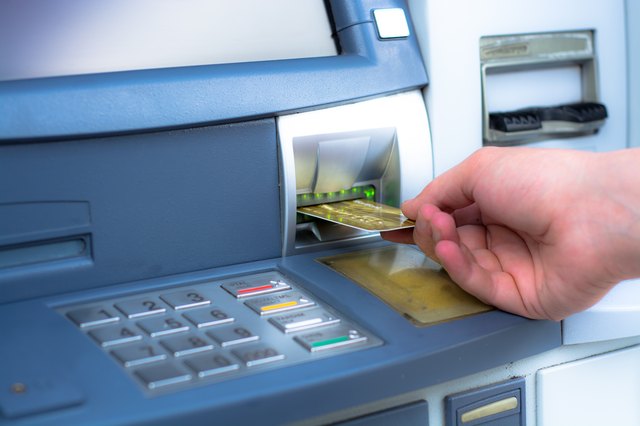 Main en insérant une carte de crédit ATM