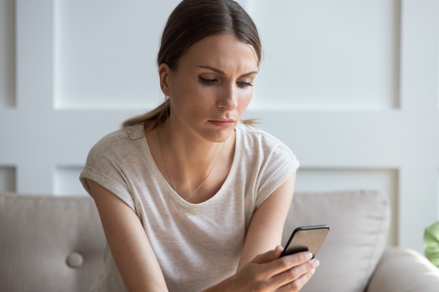 Thoughtful young woman looking at cellphone screen.