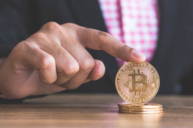 Midsection Of Businessman Holding Bitcoins On Table