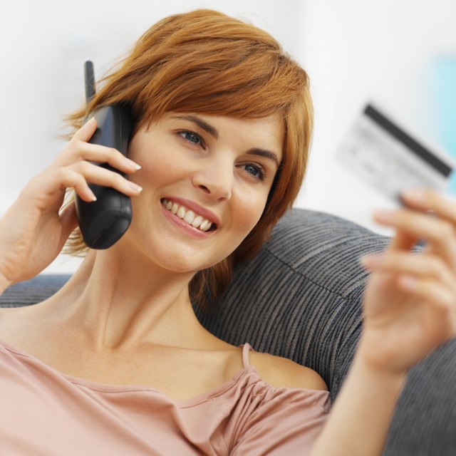 Close-up of young woman talking on mobile phone and holding credit card