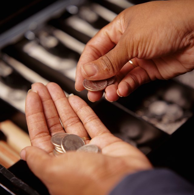 Teller counting coins at cash register, close-up, elevated view