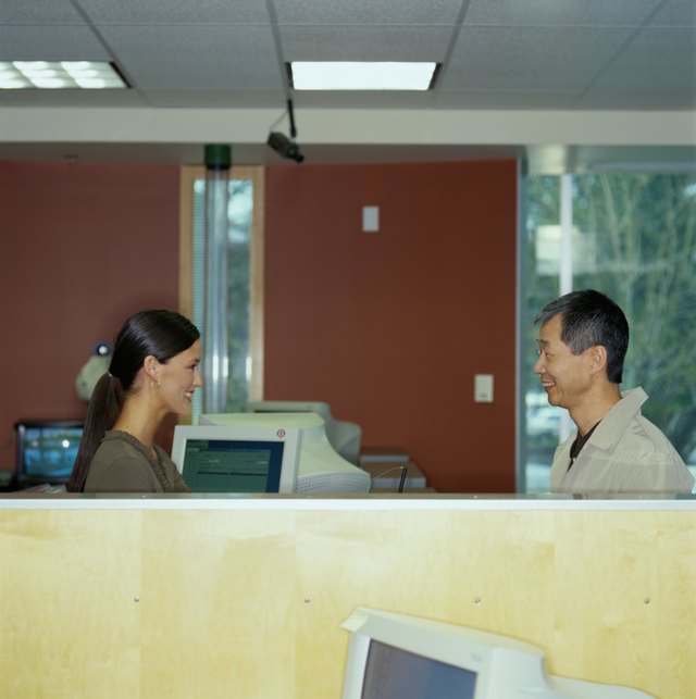 Young bank teller assisting senior customer, side view