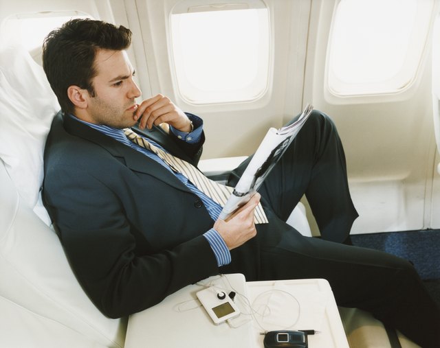 Businessman Sitting in an Aircraft Reading a Magazine