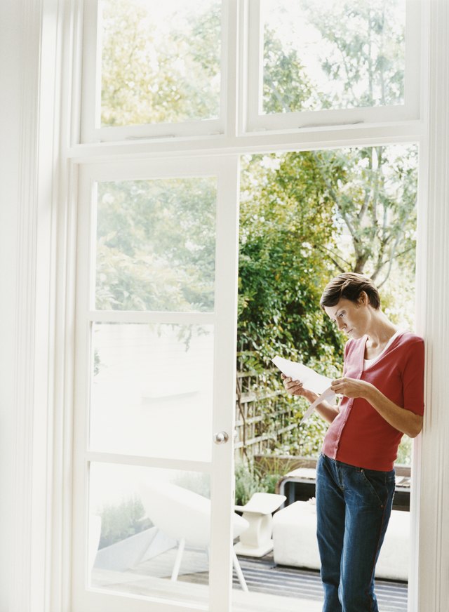 Woman Stands By an Open Patio Door Examining a Document