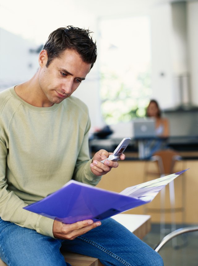 Man holding mobile phone and looking at file